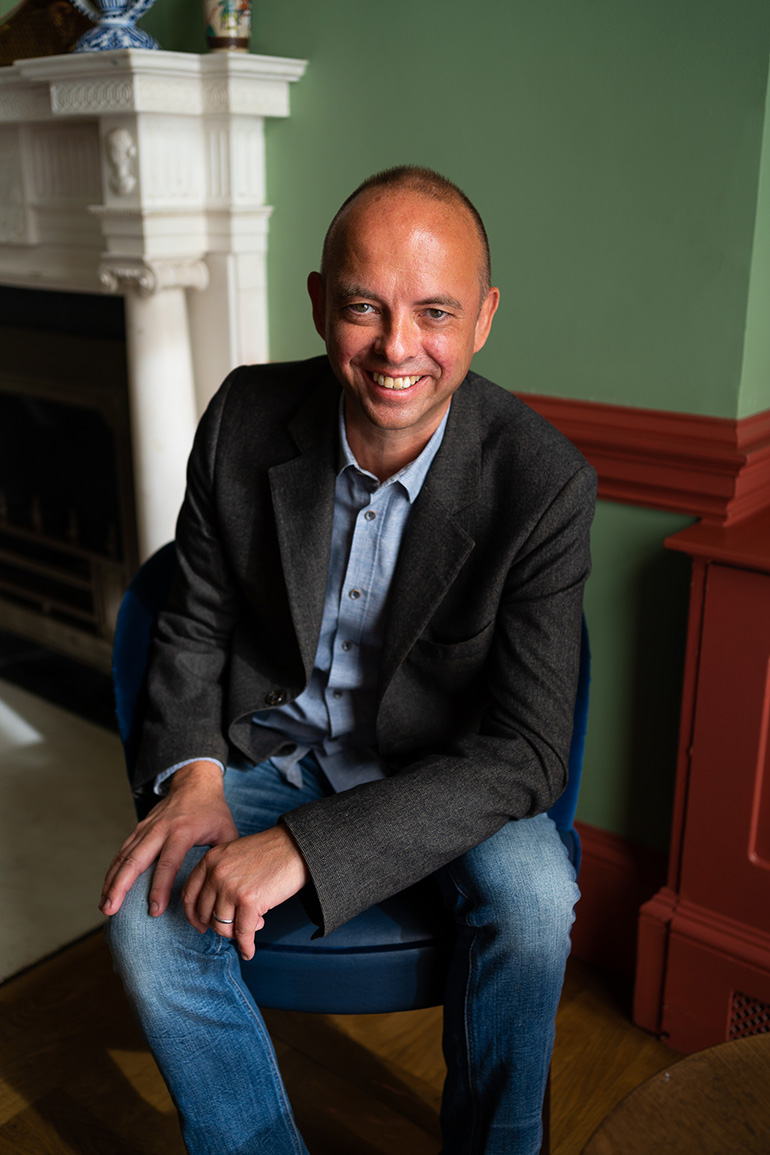 Dan Greene of Reframe Capital sits in a chair smiling at the camera